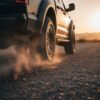 Truck driving on gravel road kicking up rocks, demonstrating the need for heavy duty truck fender flares protection.